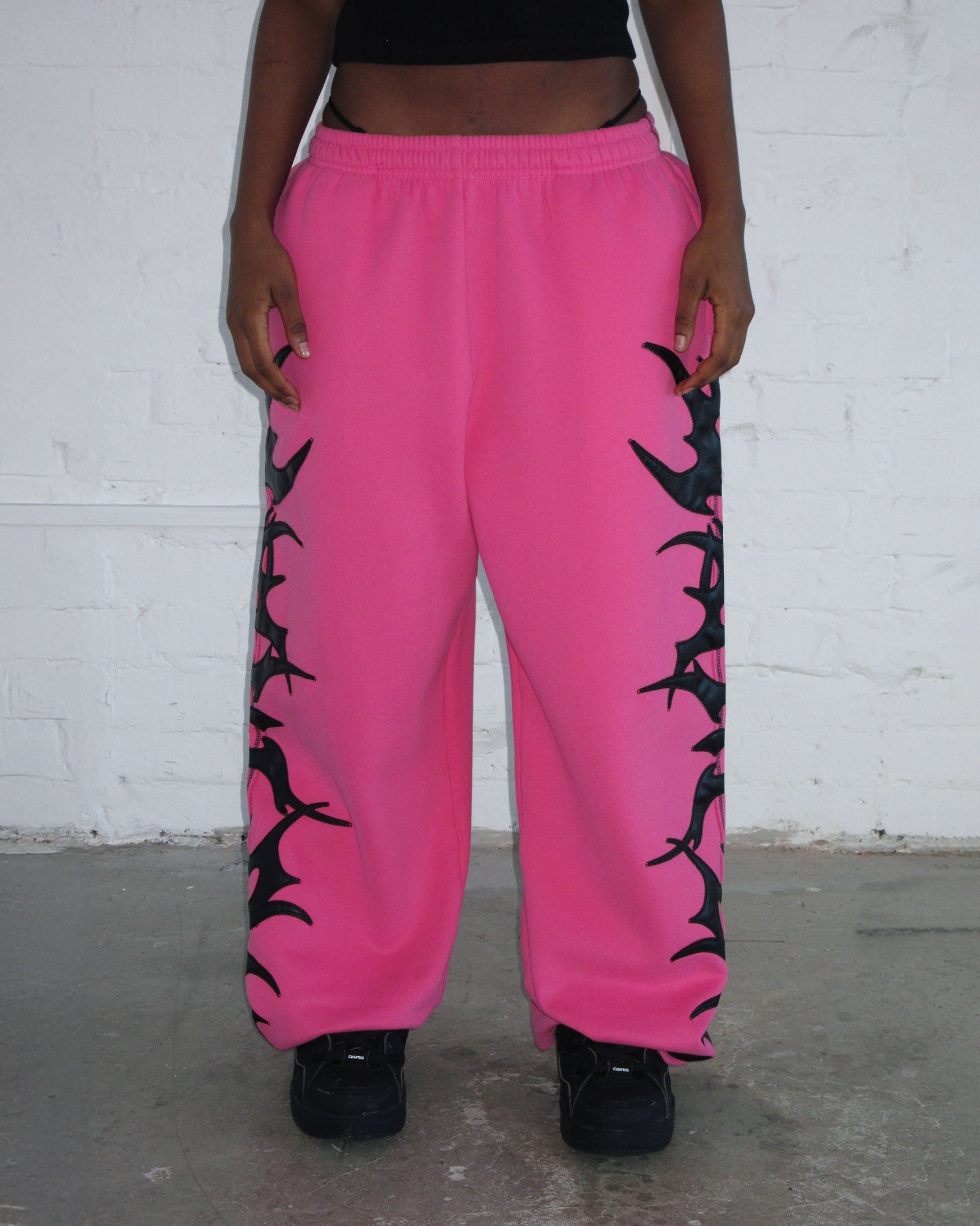 Person wearing NAMED collective FLAME SWEATPANTS PINK POISON, black shoes, and a black crop top.