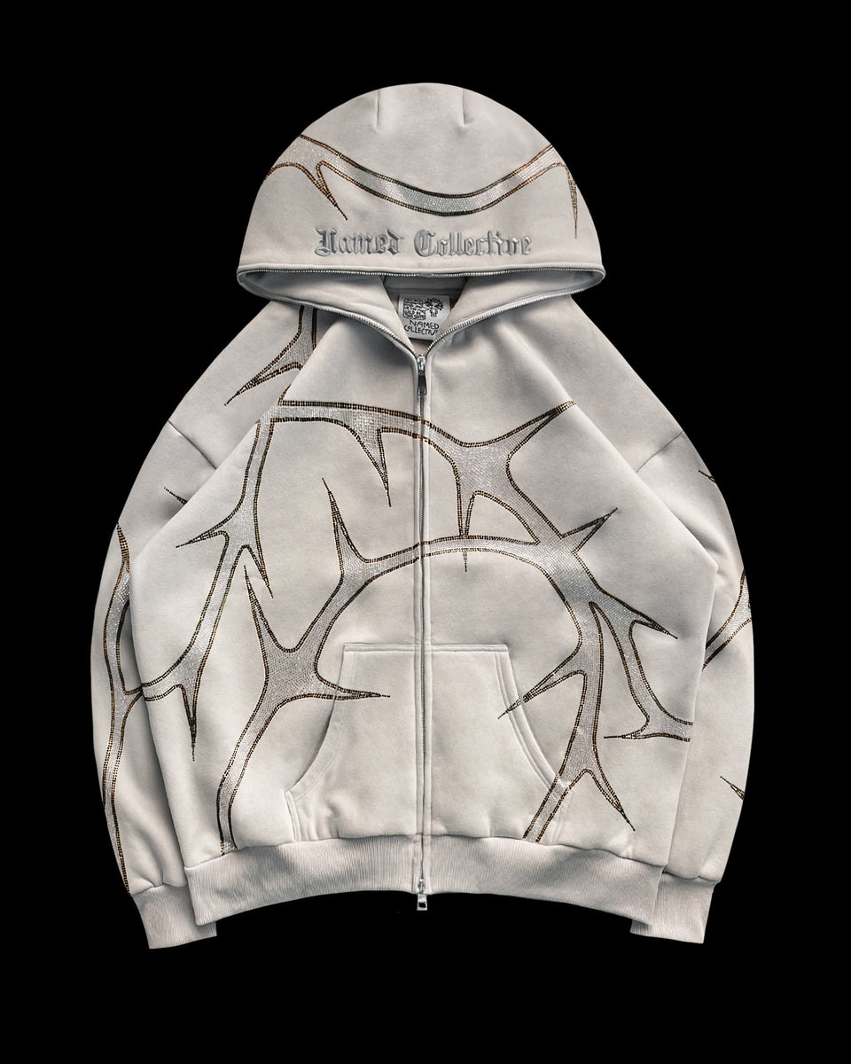 Bone zip-up hoodie with brown thorn-like patterns and NAMED COLLECTIVE® text on the hood.