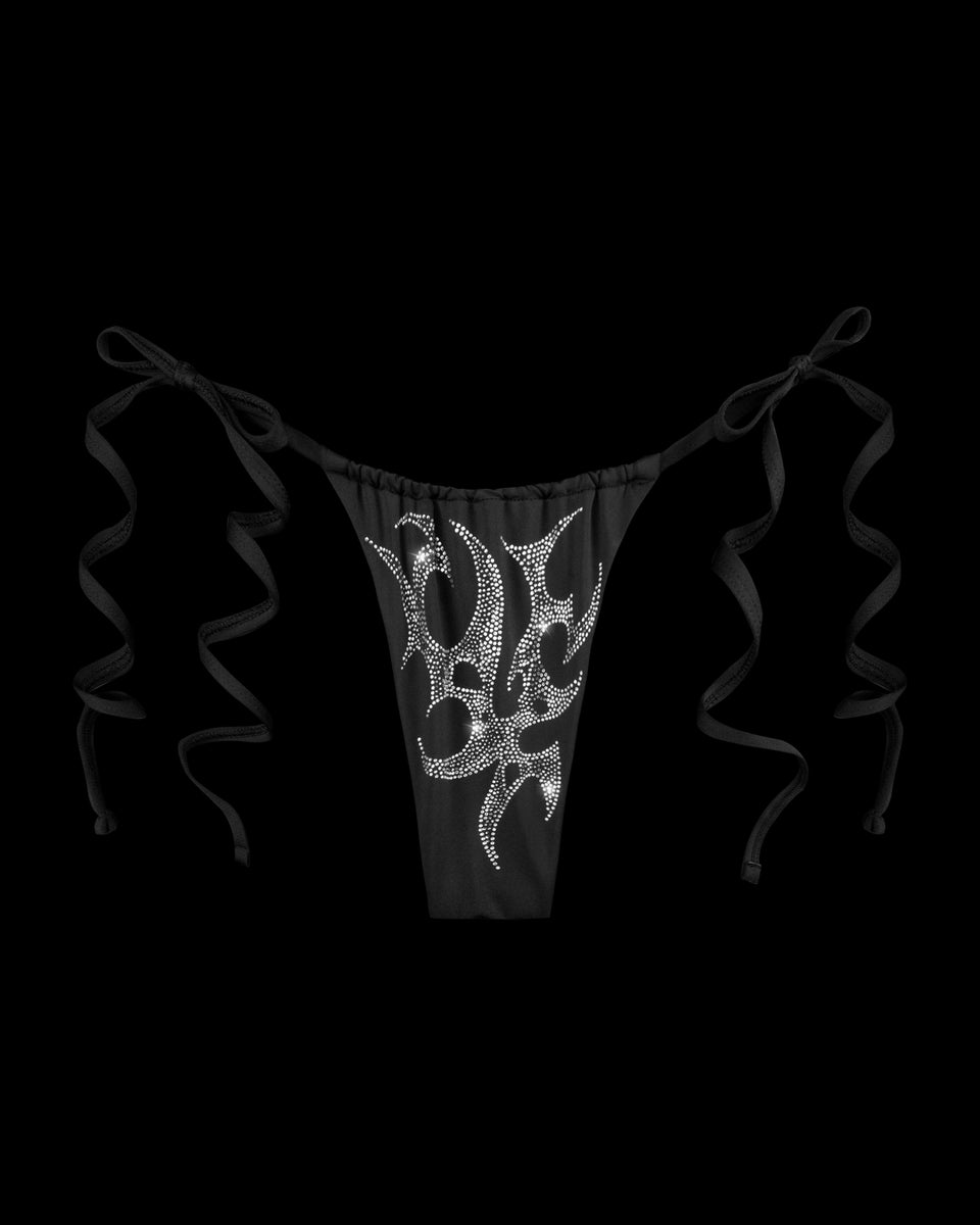 NAMED COLLECTIVE® CRASH RHINESTONE BIKINI BOTTOMS in black with side ties and silver flame detail, shown on black.