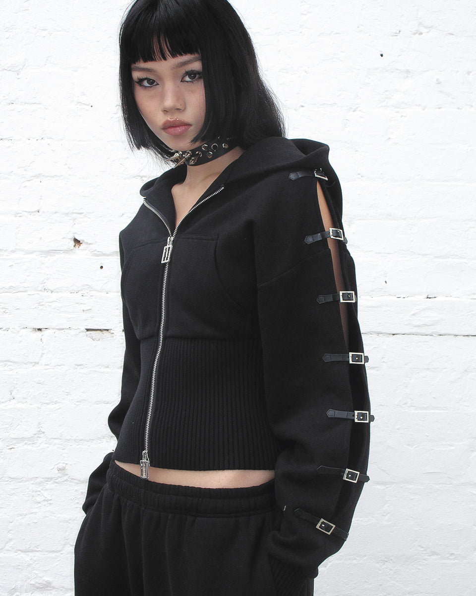 CRUSH BUCKLE FITTED WAIST ZIP HOODIE BLACK worn by a model showcasing its unique design and style.