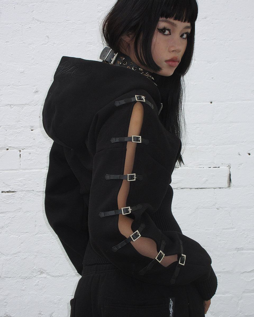 Crush buckle fitted waist zip hoodie black worn by model showcasing stylish buckle details on the sleeves.