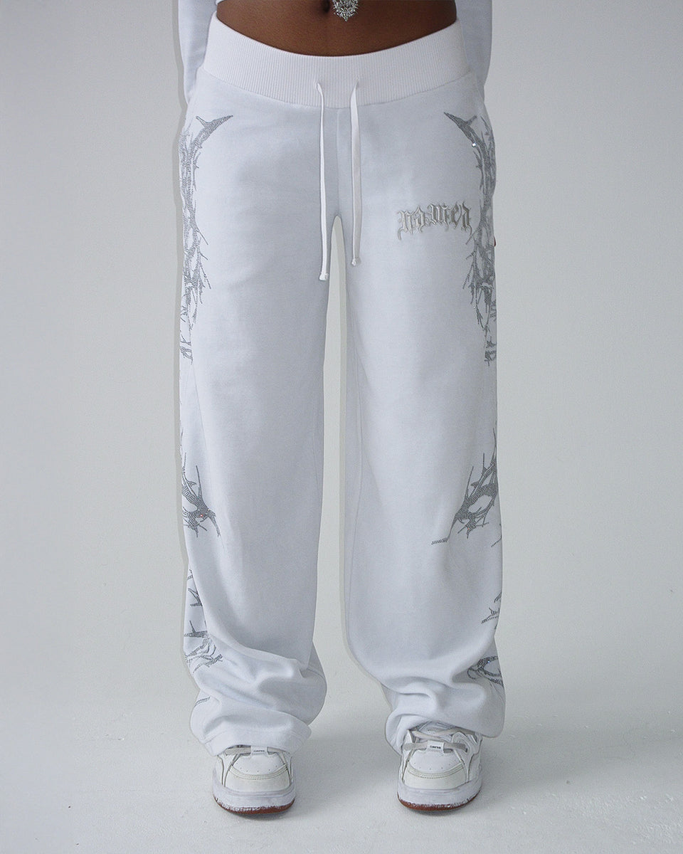 Model wears NAMED COLLECTIVE® CURSE RHINESTONE VELOUR SWEATPANTS SALT, standing against a plain background.