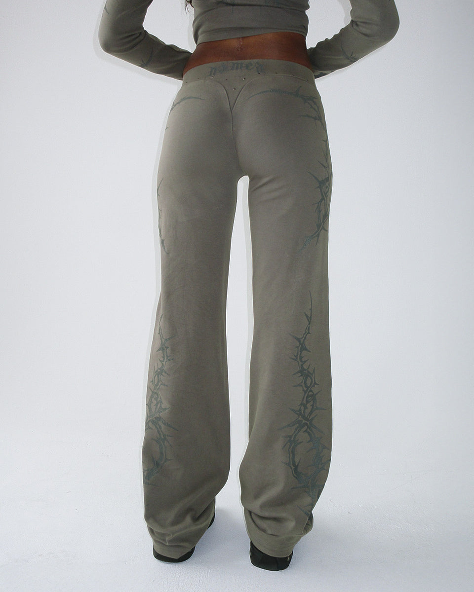 Person wears NAMED COLLECTIVE® CURSE SCULPT STRETCH PANTS in light washed army green, seen from the back on white.