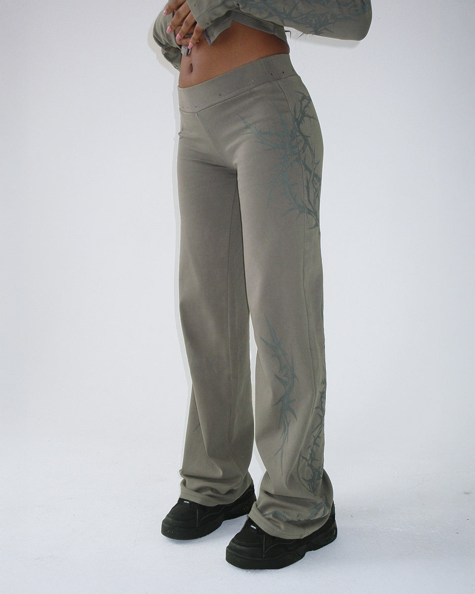 Person wearing CURSE SCULPT STRETCH PANTS LIGHT WASHED ARMY GREEN by NAMED COLLECTIVE® with black shoes and crop top.