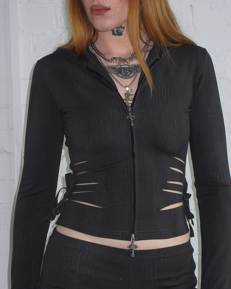 Person with long red hair in NAMED COLLECTIVE® ENVY Snakeskin Slashed Sculpt Zip Hoodie Charcoal, layered necklaces.