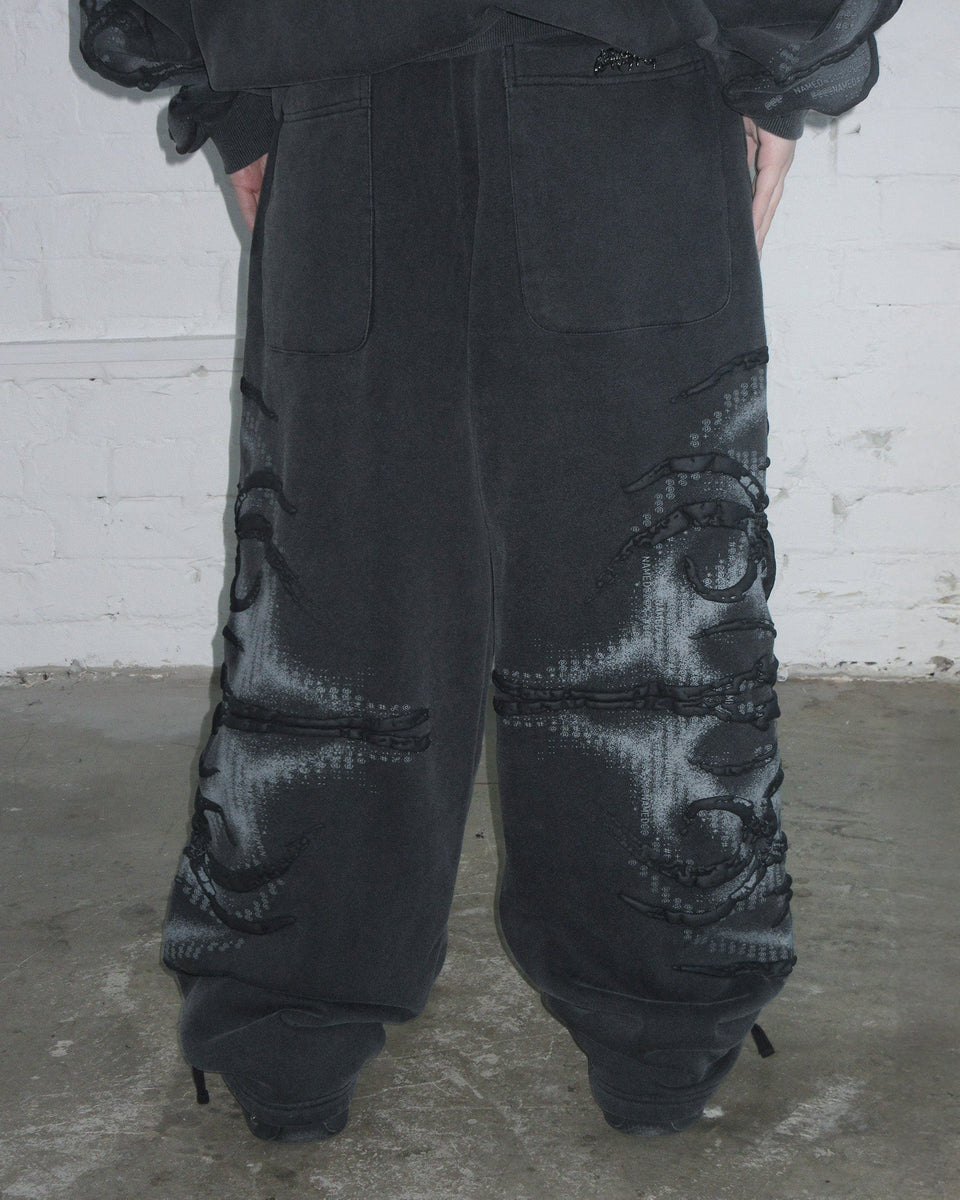 Person wearing NAMED COLLECTIVE® EUPHORIA Puff Print Oversized Sweatpants in washed charcoal, standing indoors.