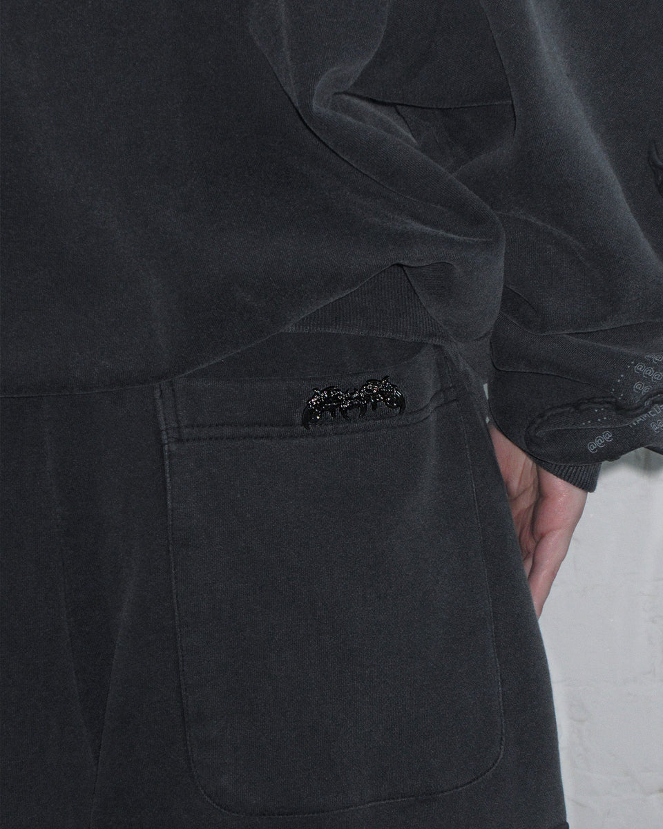 Close-up of a person in NAMED COLLECTIVE® EUPHORIA Puff Print Oversized Sweatpants in Washed Charcoal.