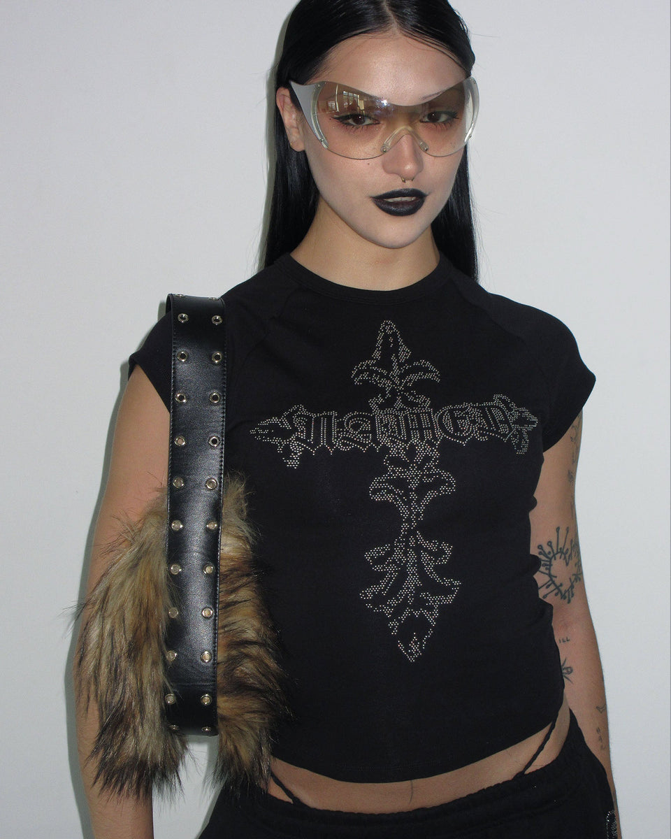 Person wearing the NAMED COLLECTIVE® FERAL STUDDED BABY TEE BLACK, sunglasses, dark lipstick, and a fur-accented bag.