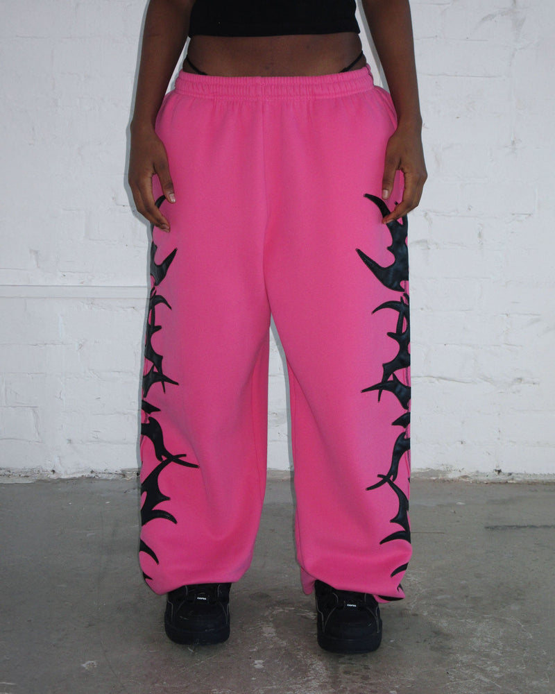 Person wearing NAMED collective FLAME SWEATPANTS PINK POISON, black shoes, and a black crop top.