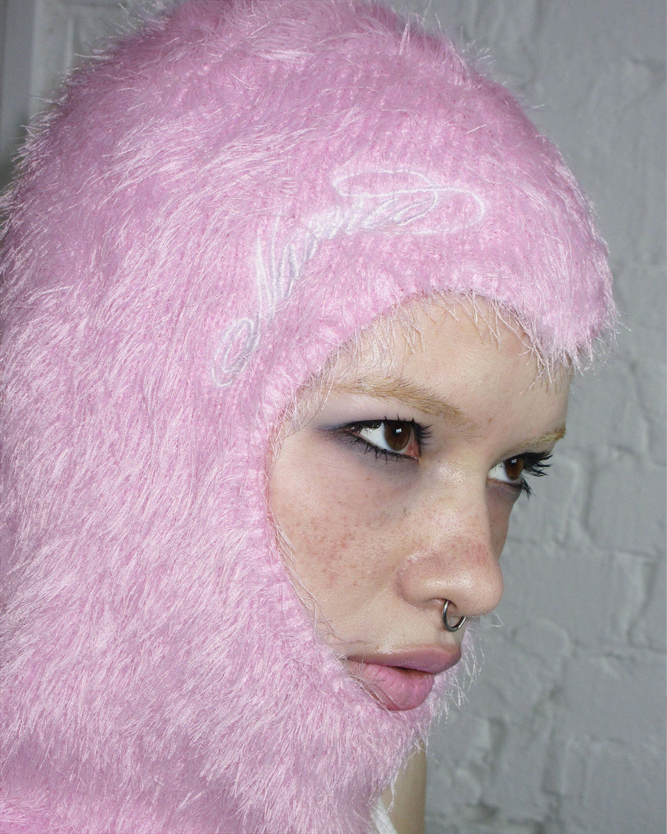 Person wearing the NAMED COLLECTIVE® PREY FLUFFY KNIT HEART BALACLAVA in baby pink, looking to the side.