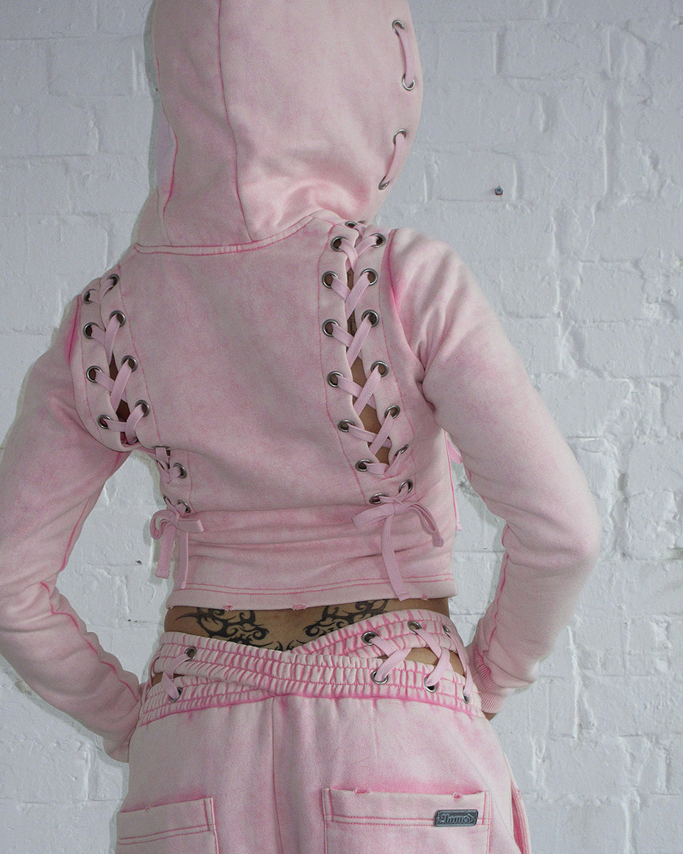 Fitted pink hoodie with lace-up design, made from organic cotton and recycled polyester fleece, acid washed finish.