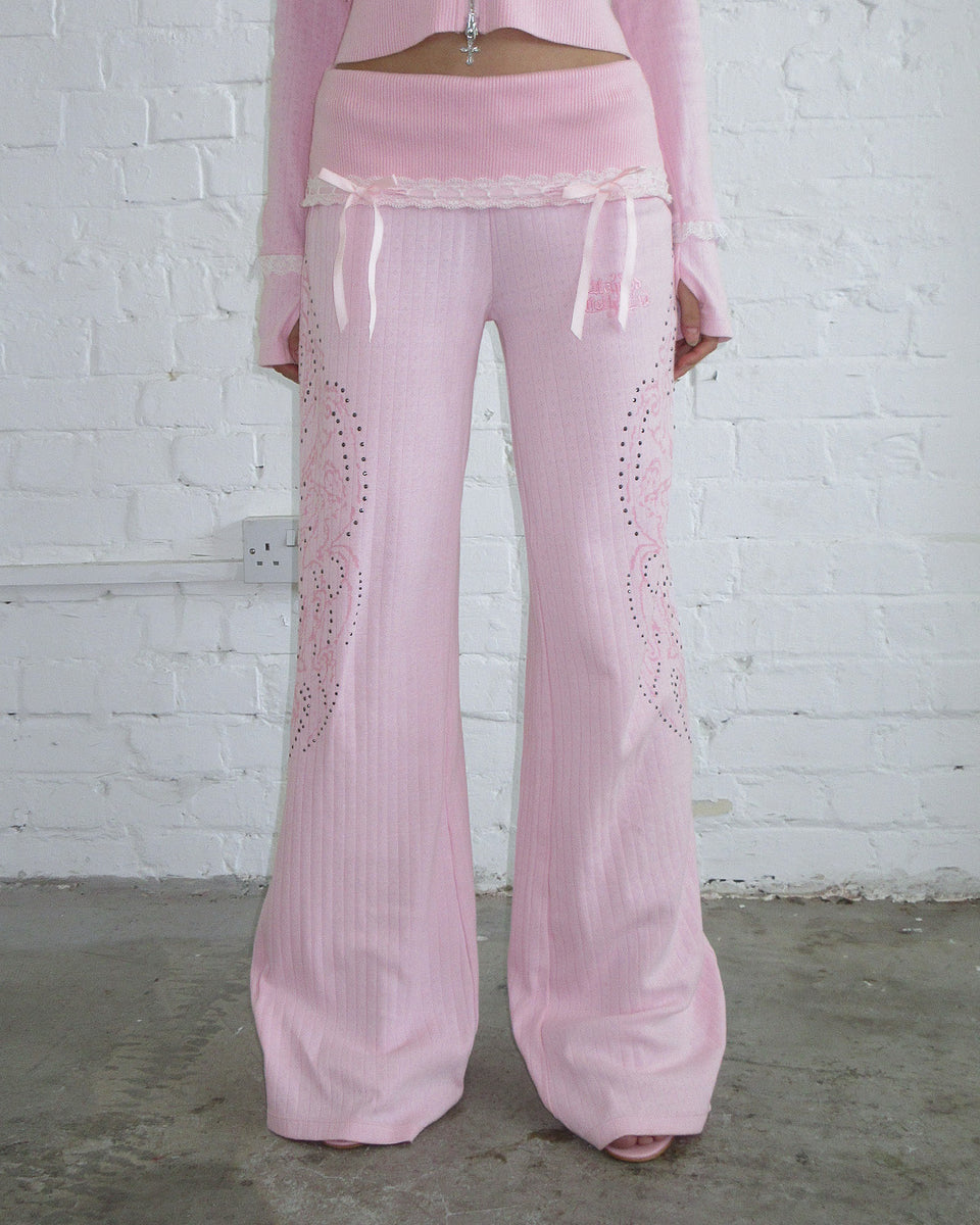 Model wears NAMED COLLECTIVE® WHISPER RIBBON POINTELLE SCULPT PANTS in Baby Pink against a white brick wall.
